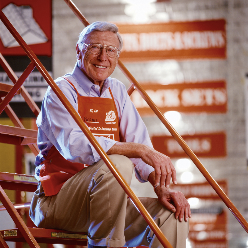 Bernie Marcus in Apron sitting on ladder.